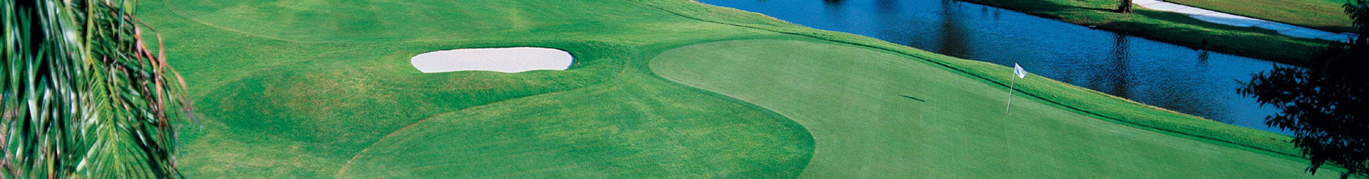 A picturesque golf course featuring a manicured putting green and serene water body.
