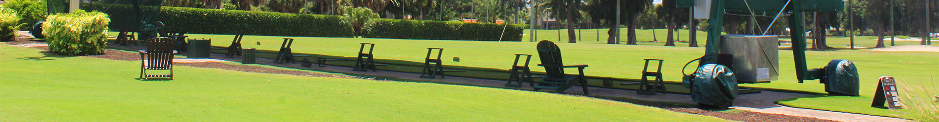 A serene outdoor space featuring a green lawn and wooden rocking chairs along a sunny path.